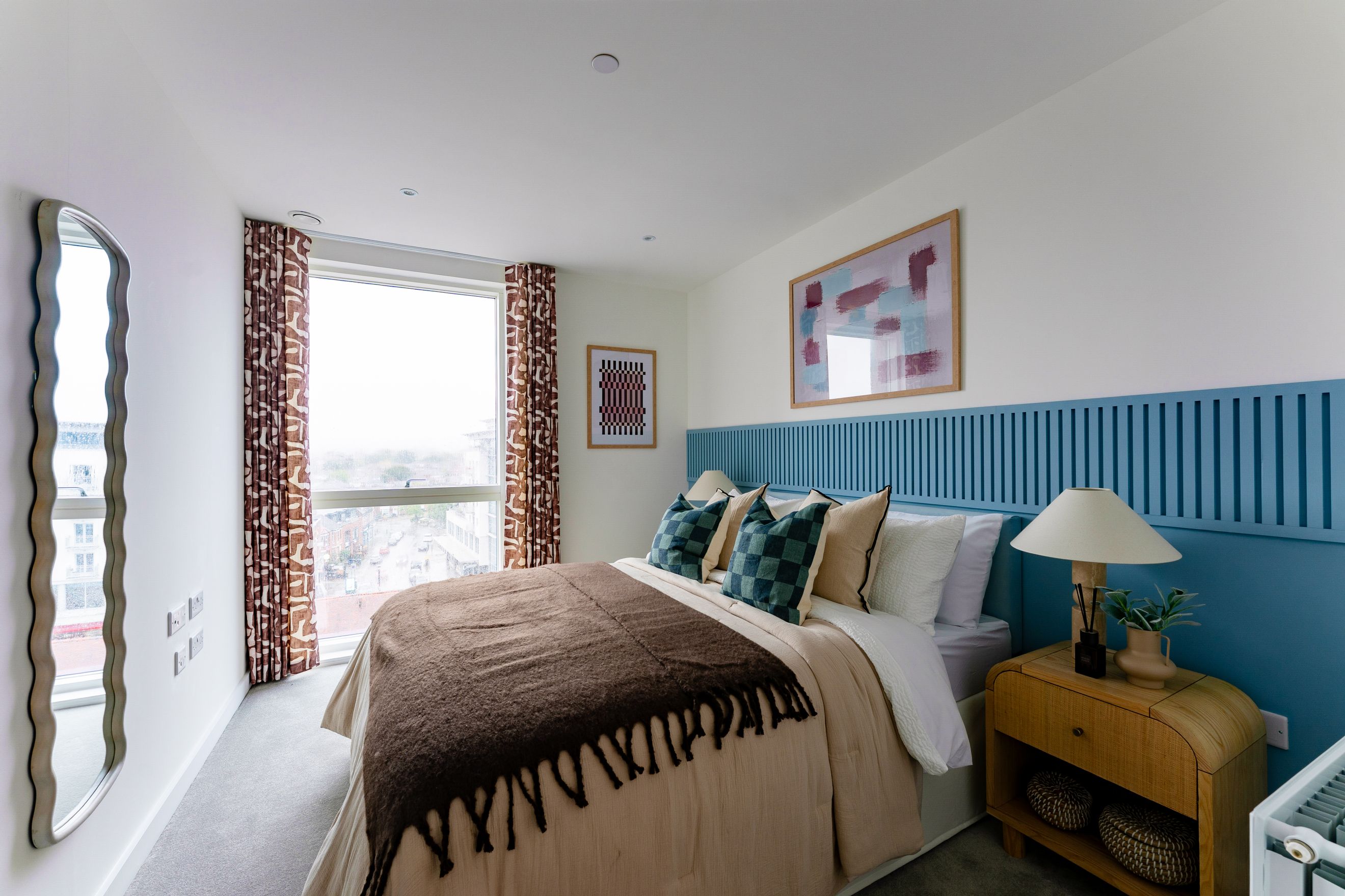 A bedroom with a bed, pillows, curtains, and a nightstand.