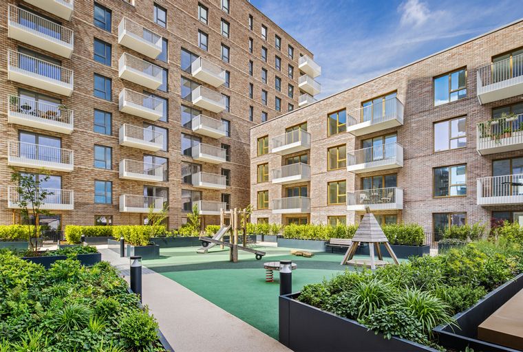 A modern apartment complex courtyard with a playground and balconies.