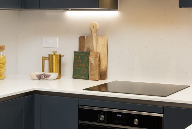 A modern kitchen countertop with dark cabinets, white quartz, and various kitchen items.