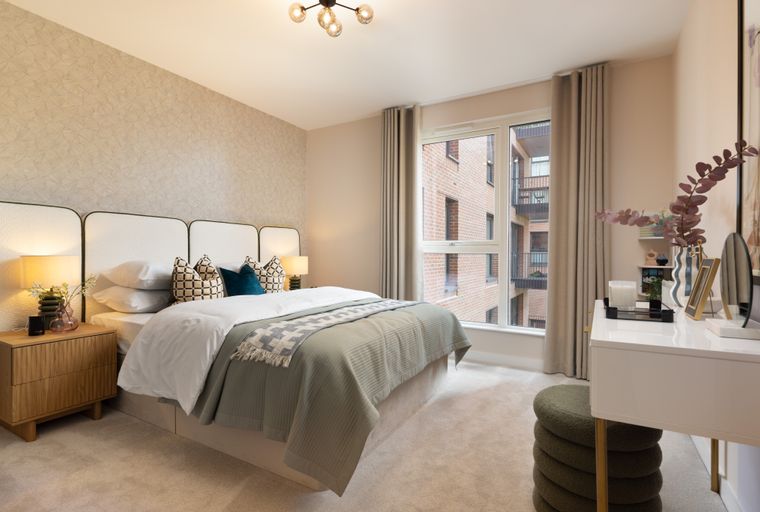 A bedroom with a bed, nightstand, and a vanity table.