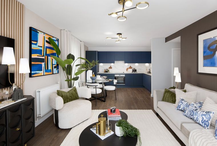 A living room and kitchen area with a sofa, chairs, dining table, and kitchen cabinets.