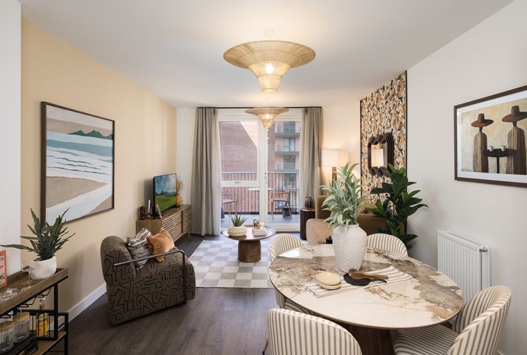 A dining and living area with a marble-top table, striped chairs, a patterned armchair, and a rattan pendant light.