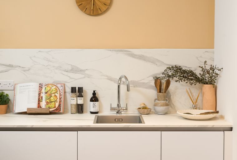 A kitchen counter with a sink, faucet, cookbook, and decorative items.