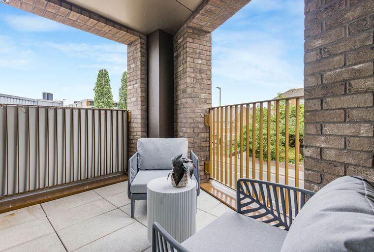 A balcony with two chairs, a table, and a plant.