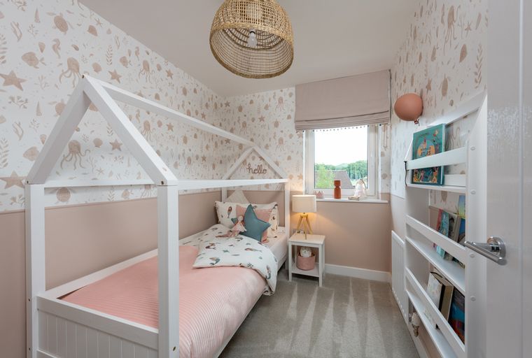 A child's bedroom with a house-shaped bed, themed wallpaper, and a bookshelf.