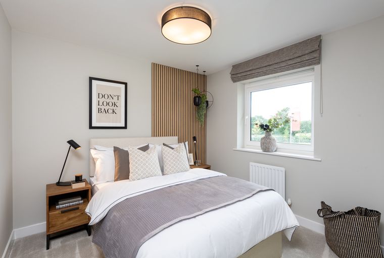 A bedroom with a bed, bedside table, and a window.