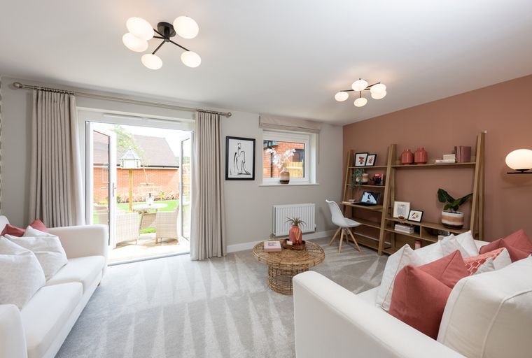 A living room with two white sofas, a coffee table, and a workspace.