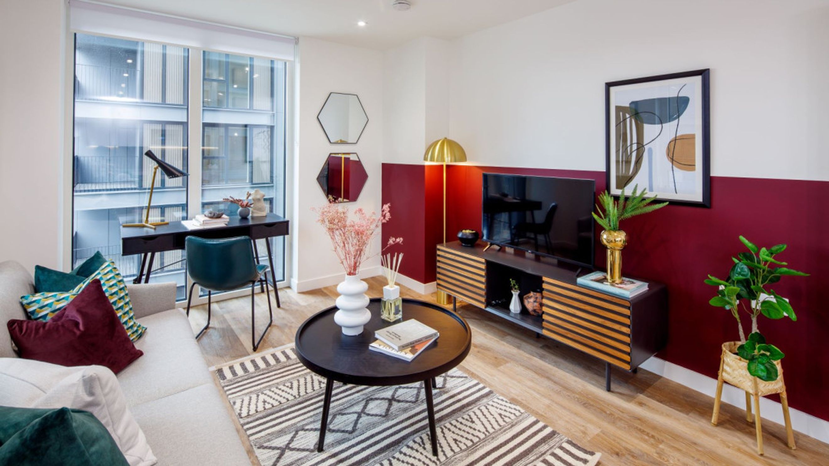 A living room with a sofa, coffee table, and a desk by a large window.