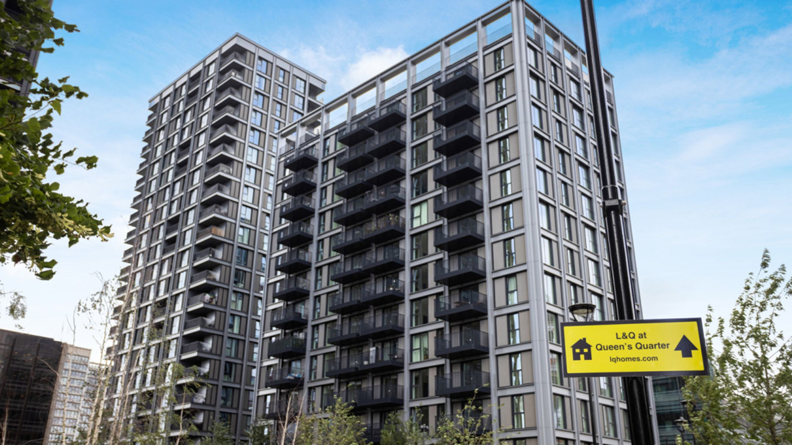 A modern apartment building with balconies and a yellow sign.