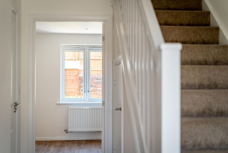 A hallway with a staircase, a window, and a radiator.