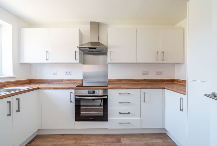 A modern kitchen with white cabinets, wooden countertops, and stainless steel appliances.