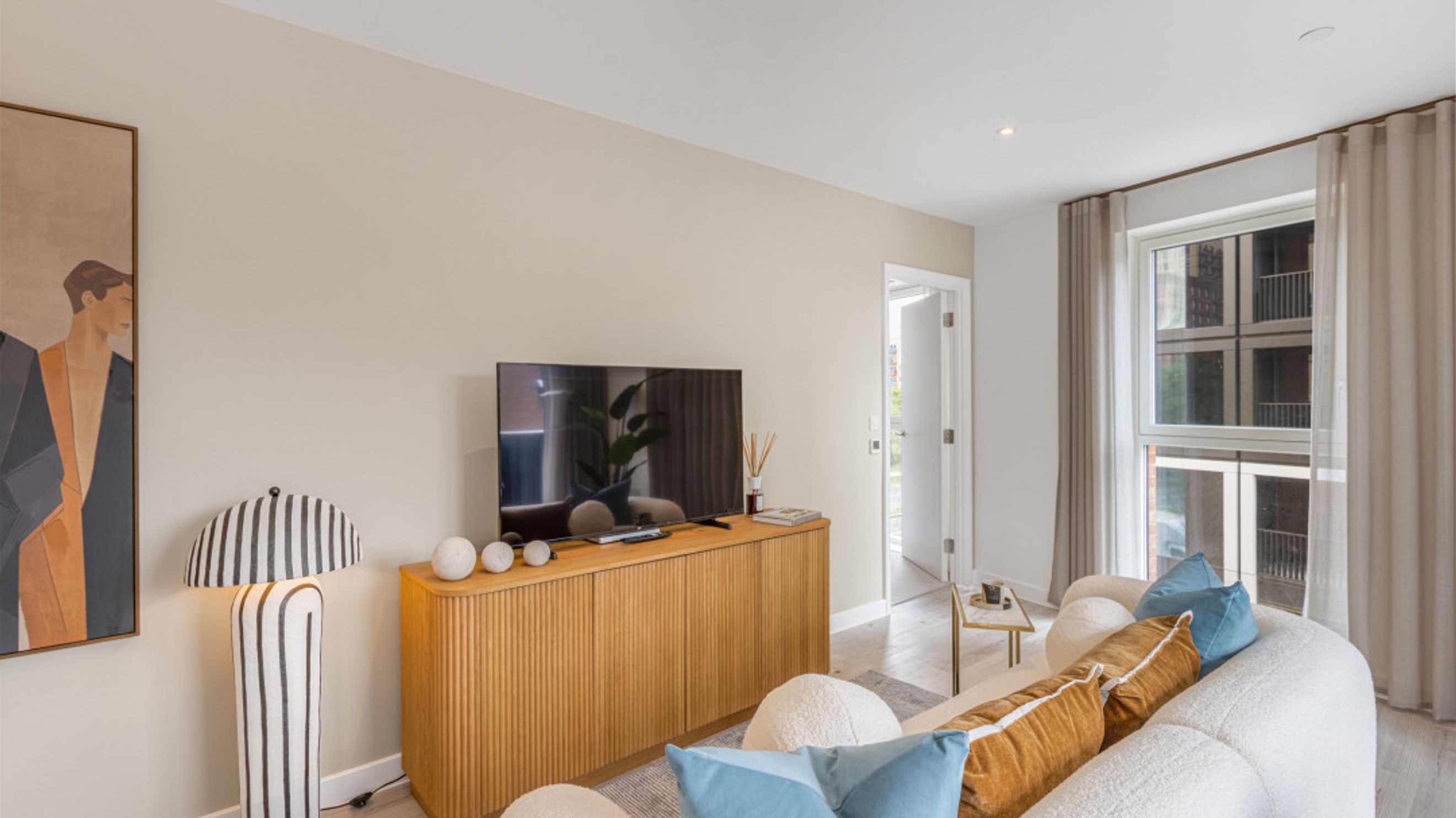 A living room with a television, a wooden cabinet, a floor lamp, and a sofa.