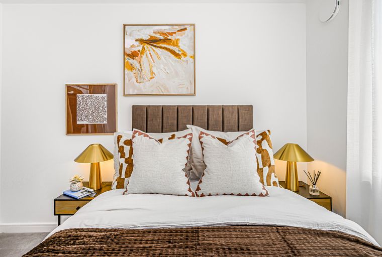 A bedroom with a bed, headboard, pillows, bedside tables, and lamps.