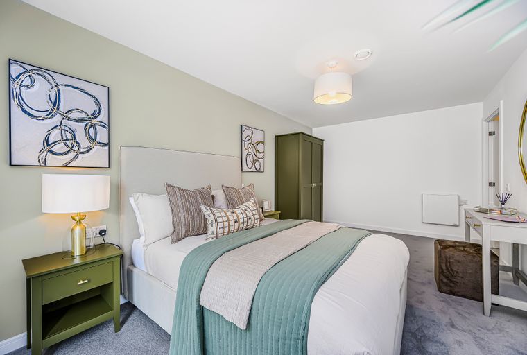 A bedroom with a bed, nightstand, wardrobe, and artwork.