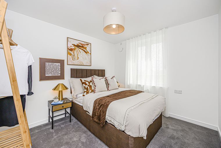 A bedroom with a bed, bedside table, and artwork.