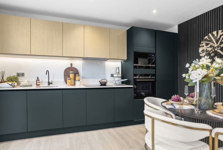 A modern kitchen and dining area with dark cabinets, wood upper cabinets, integrated appliances, and a dining table with chairs.