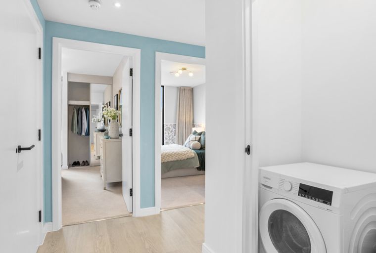 A hallway with a washing machine, a closet, and a bedroom.