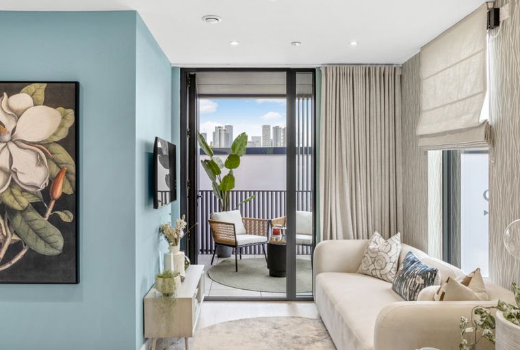 A living room with a sofa, a balcony, and a large floral painting on a blue wall.