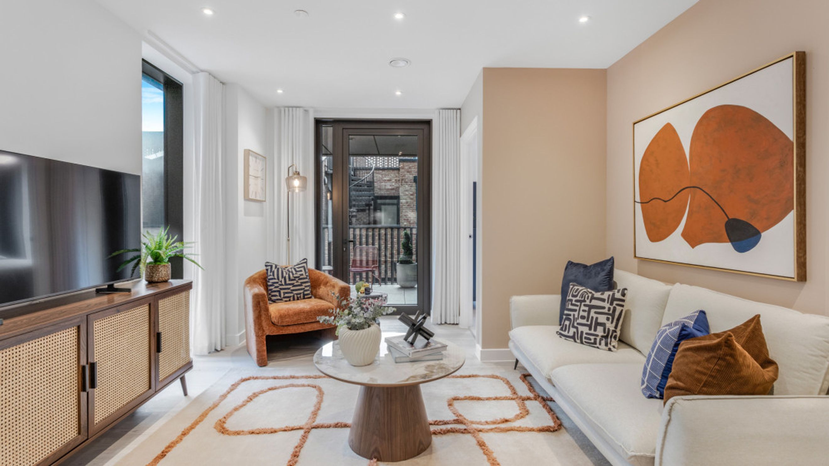 A living room with a sofa, armchair, coffee table, and television.