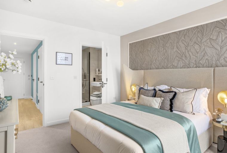 A bedroom with a bed, pillows, a bedside table, and a doorway to a bathroom.