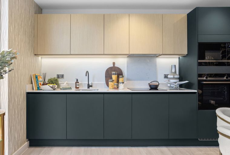 A modern kitchen with dark lower cabinets, light wood upper cabinets, a sink, and integrated appliances.