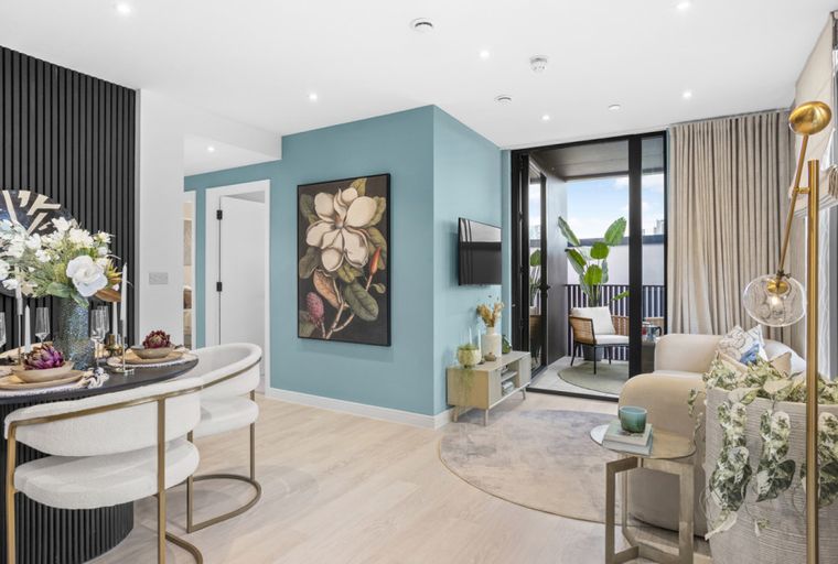 A dining area and living room with a round table, chairs, a sofa, and a balcony.