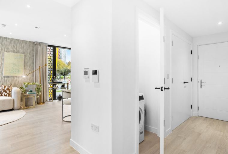 A hallway and living area in a modern apartment with doors and a sofa.