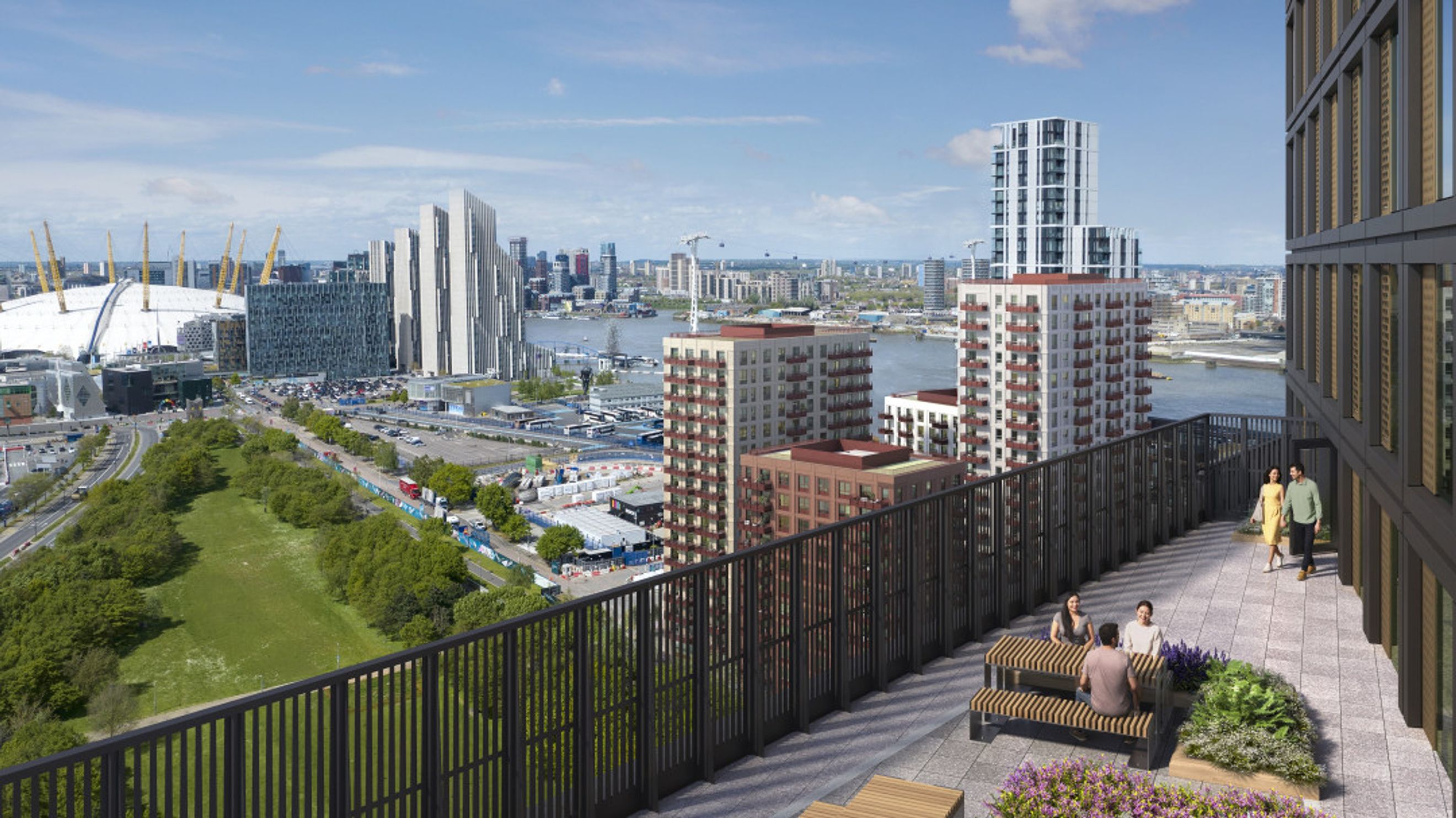 A rooftop terrace with people dining at a table and a couple walking, overlooking a city skyline with buildings and a river.