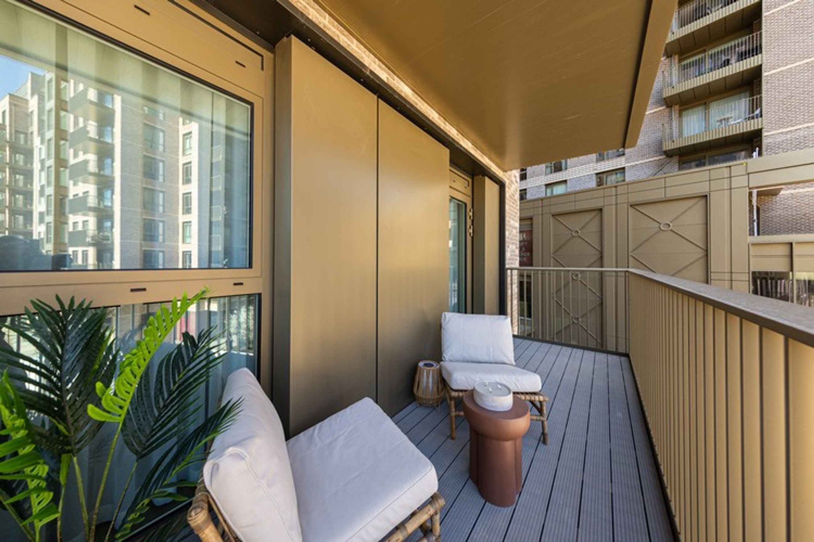 A balcony with two chairs, a small table, and a plant.