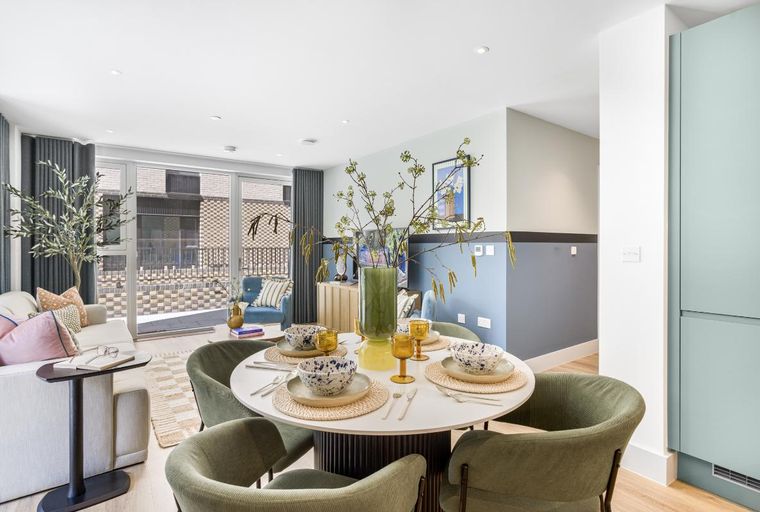 A dining area with a round table, chairs, and a vase of flowers.