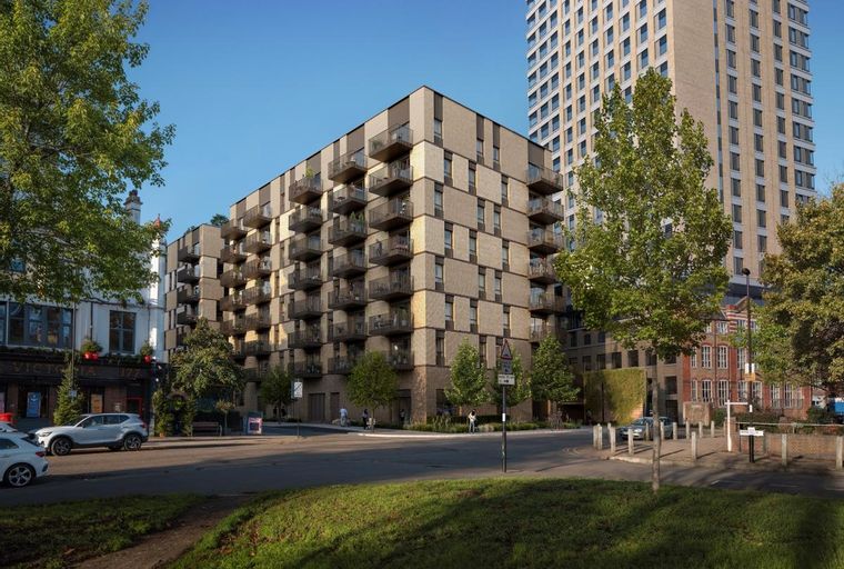 A modern apartment building with balconies and a tall building in the background.