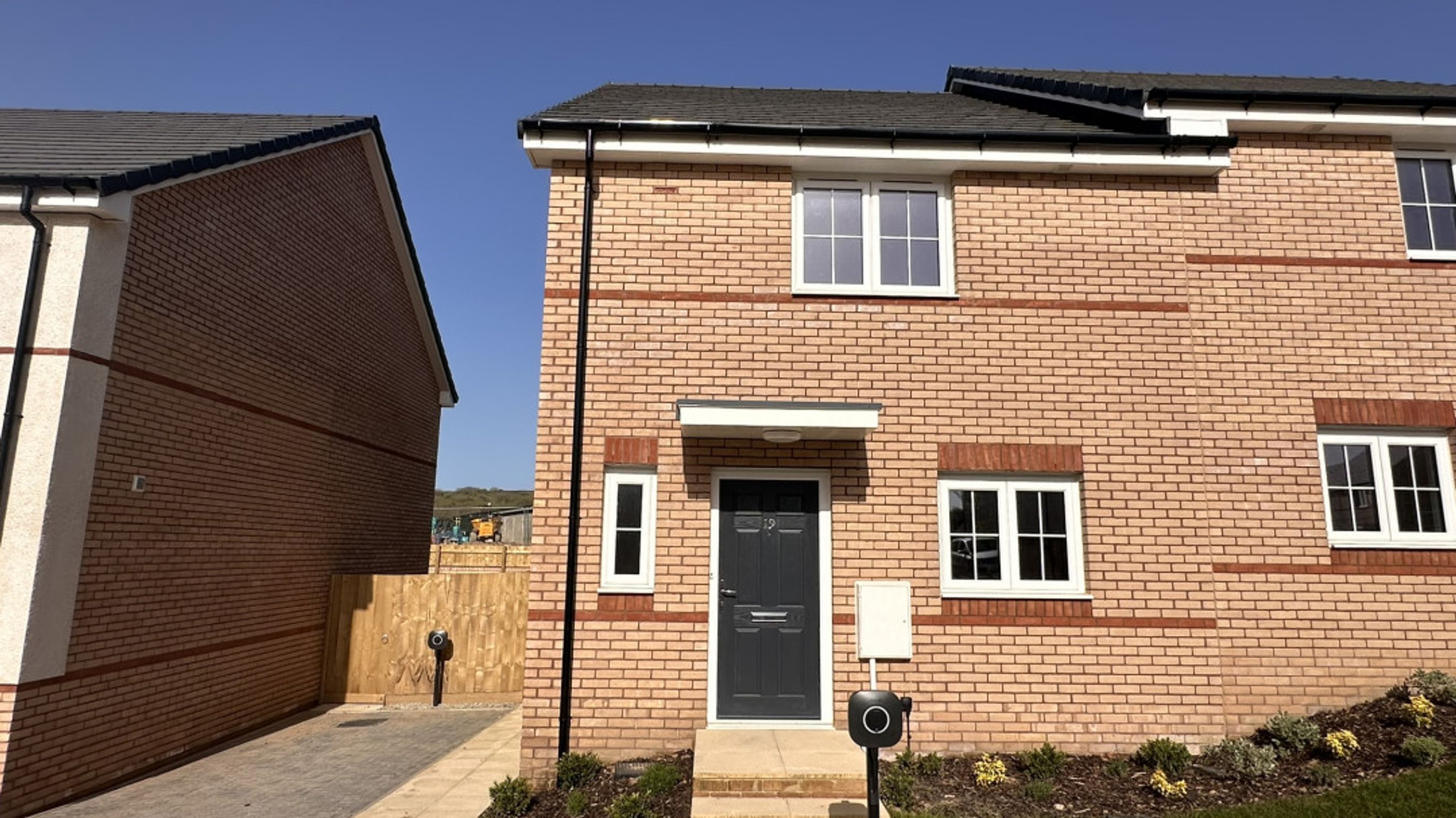 A new brick house with a dark grey front door and white-framed windows.