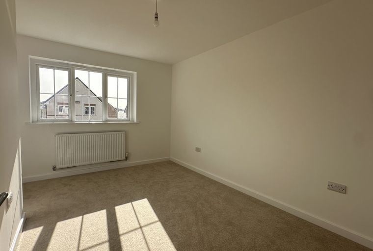 A bedroom with a window and a radiator.