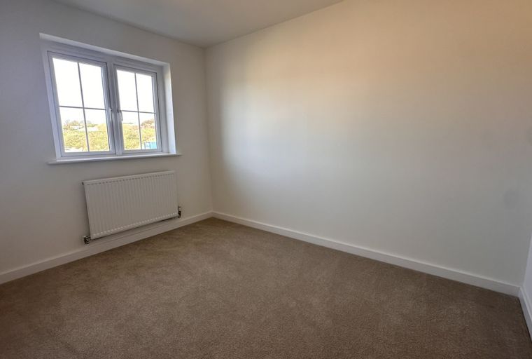 A bedroom with a window and a radiator.