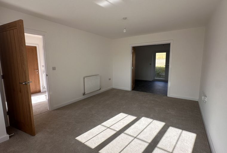 A room with a carpet, radiator, and two doorways.