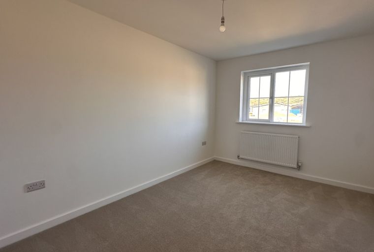 A bedroom with a window and a radiator.