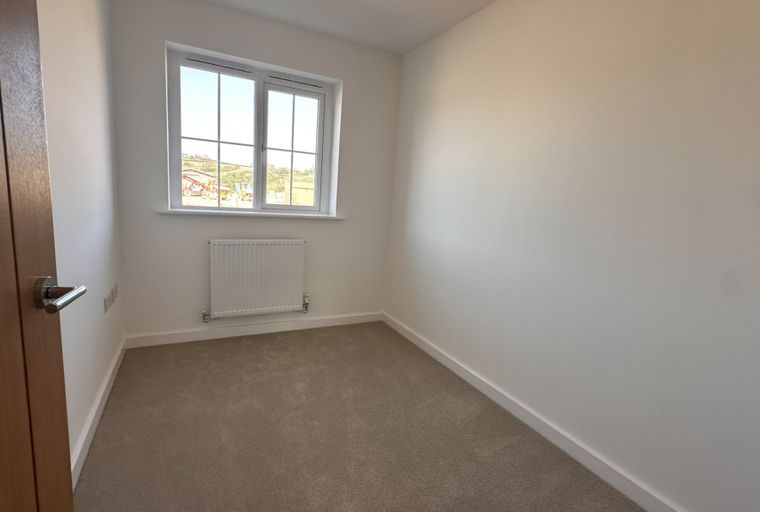 A room with a window, a radiator, and a door.