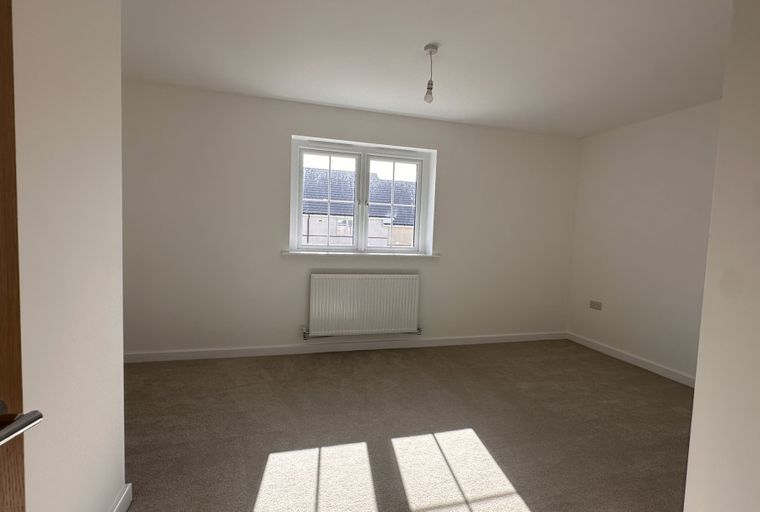 A bedroom with a window and a radiator.