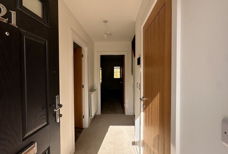 A hallway with a black front door and two interior doors.
