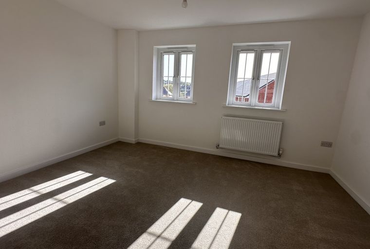 A bedroom with two windows and a radiator.