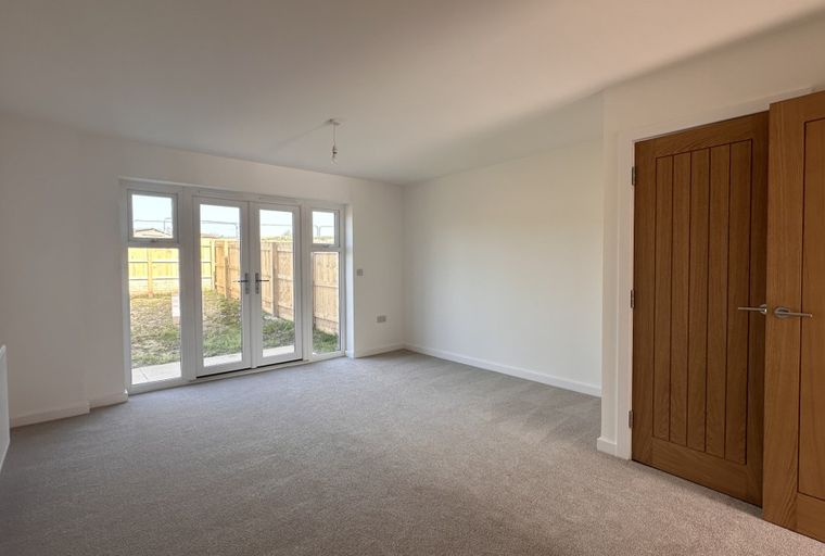 A living room with French doors leading to a garden and wooden doors.