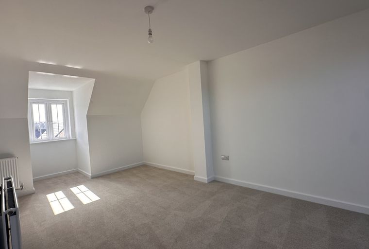 A room with a window, carpet, and radiator.
