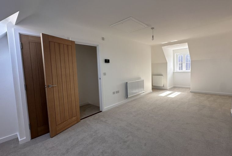 A bedroom with wooden doors, radiators, and a window.