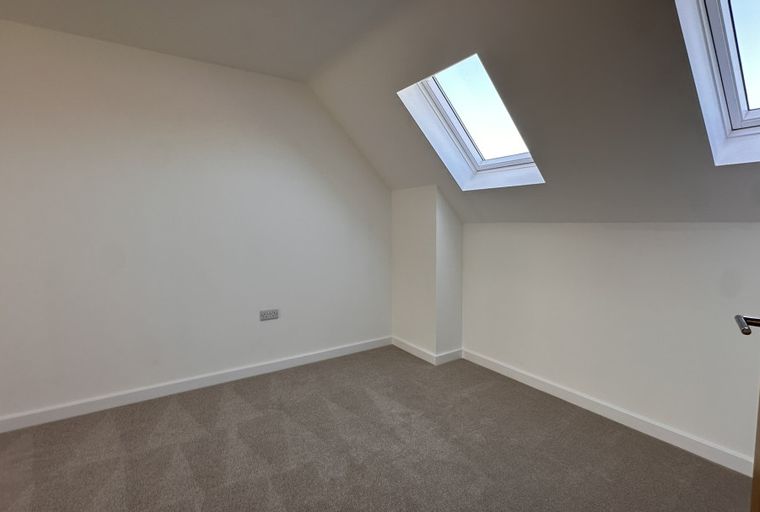 A room with carpet, white walls, and skylights.