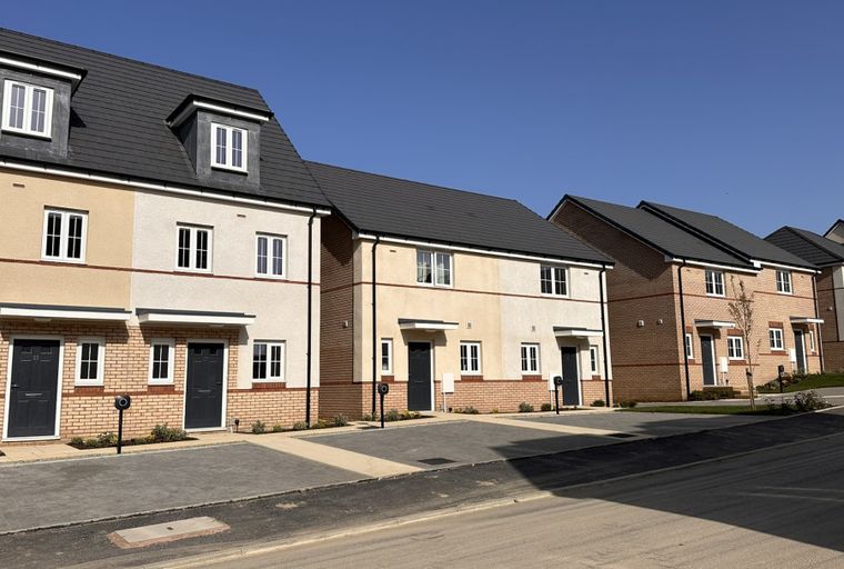 A row of modern townhouses with stucco and brick exteriors under a clear blue sky.