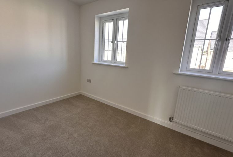 A bedroom with two windows and a radiator.