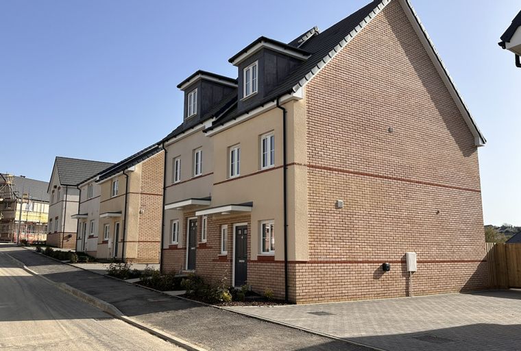 A row of new townhouses with brick and stucco exteriors under a clear blue sky.