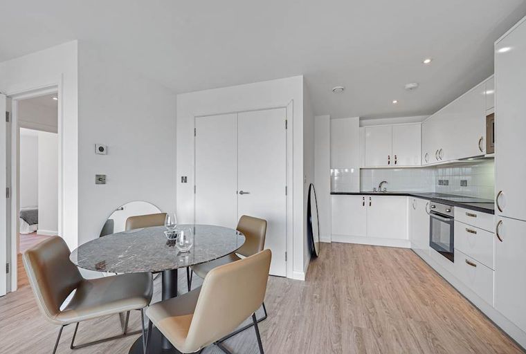 A dining area and kitchen with a table, chairs, and white cabinets.