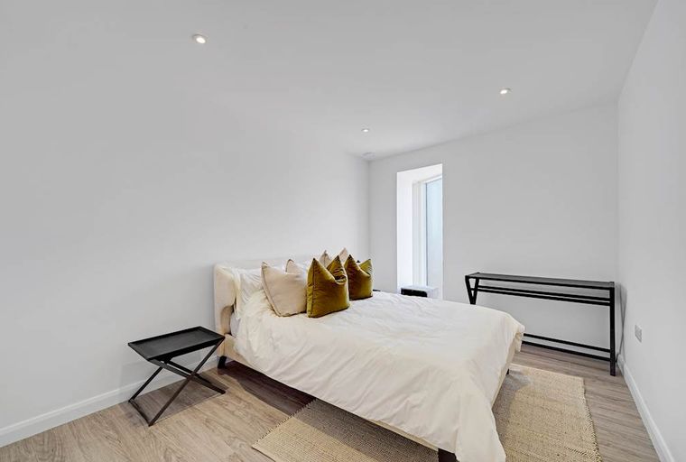A bedroom with a bed, pillows, and two side tables.