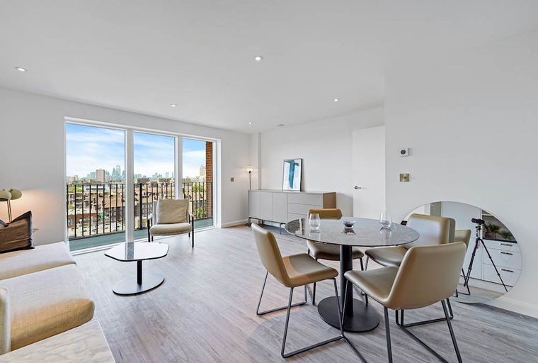 A living and dining area with a balcony overlooking a city skyline.